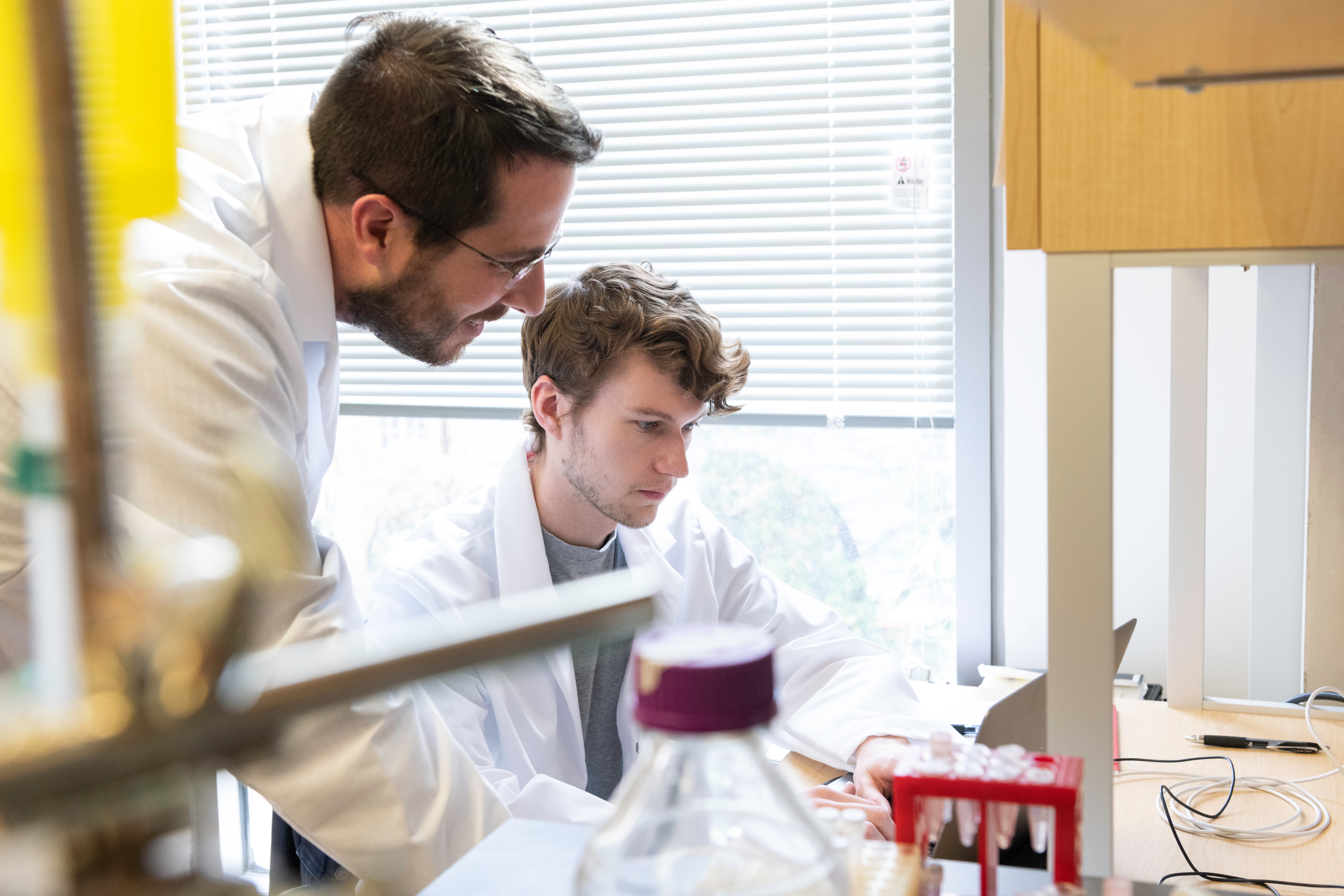 Student and supervisor looking at a computer screen together in a laboratory.